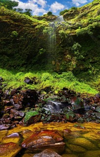 Small waterfall with clear water flowing down over moss-covered rocks, Poca da Inglesa waterfall,