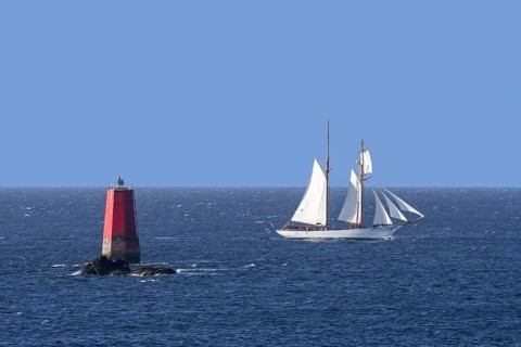 Sailing ship passing red sea mark, seamark, navigation mark on the shallows Les Vieux Moines at