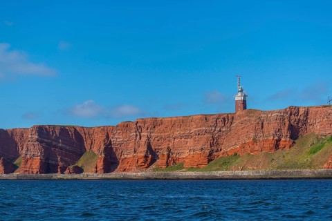 Red mottled sandstone cliff edge, Heligoland high sea island, lighthouse, geology, scree, blue sky,