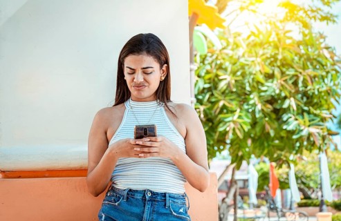 Girl with the cell phone receiving an unpleasant message. Young woman with cell phone reading a