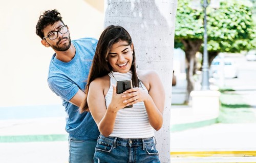 Jealous boyfriend spying on his girlfriend's cell phone in the park, Jealous man spying on his