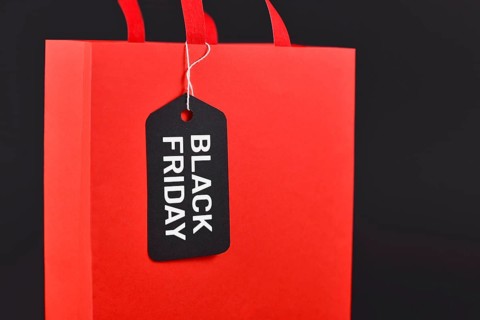 Black Friday sale label on red paper shopping bag on black background