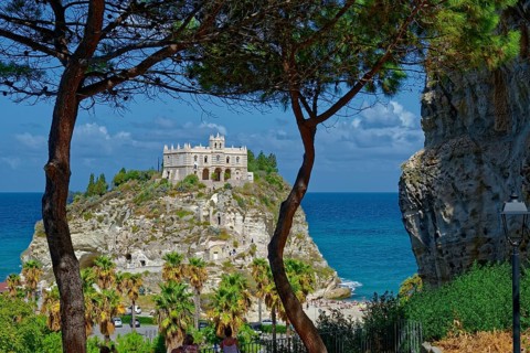 View through pine trees to the medieval church Santuario di Santa Maria dell Isola di Tropea built