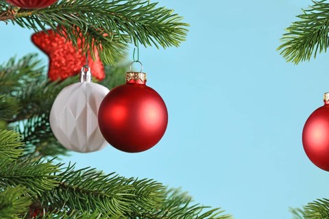 Red Christmas baubles on Christmas tree on blue background with copy space