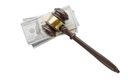 Overhead of gavel resting on stacks of thousands of dollars isolated on a white background