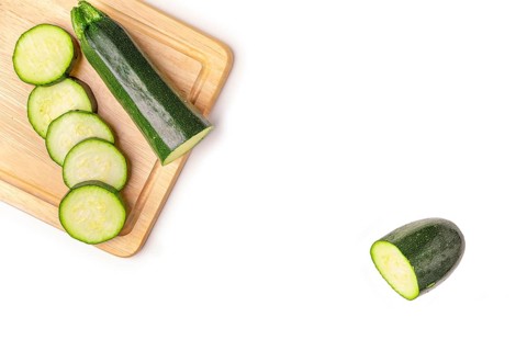Courgettes (Cucurbita pepo), cut open, on wooden board, on white, copy room