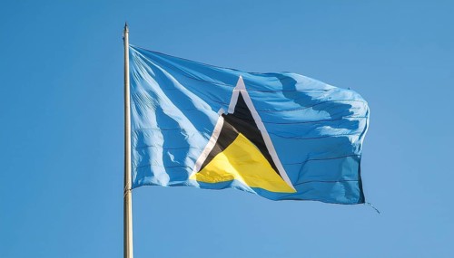 The flag of St Lucia, Caribbean, flutters in the wind, isolated against a blue sky