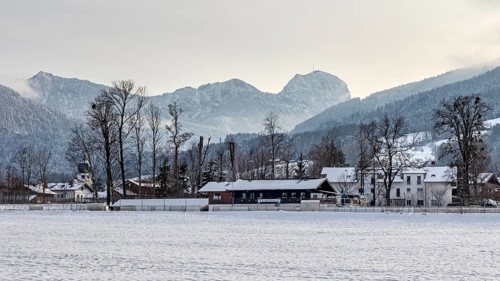 Snow-covered village in front of a mountain range with a peaceful winter atmosphere, Bad Feilnbach,