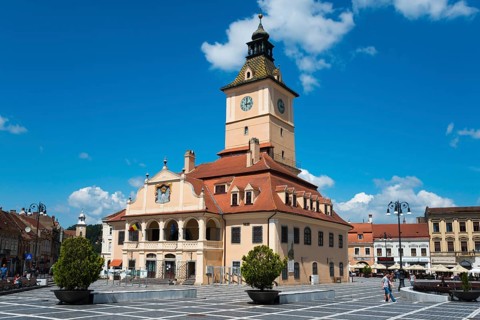 A busy town square with a town hall and a large clock on a clear day, Old Town Hall at Piata