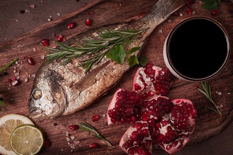 Fried dorado fish, with spices and herbs, on a wooden board, pomegranate sauce, close-up, no people