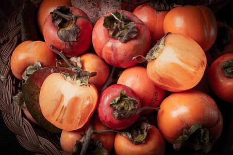 Fresh persimmon in a basket, with leaves, top view, no people