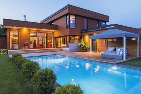 Rear of modern cube style home with stained horizontal wood cladding, in-ground swimming pool and