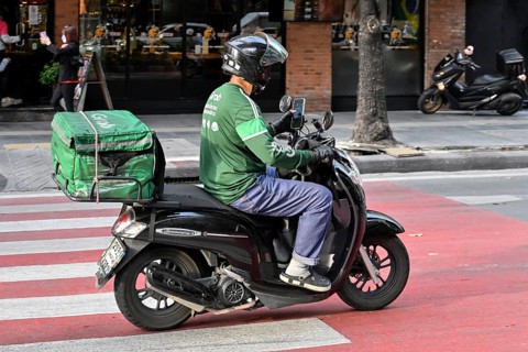Grab scooter driver typing on mobile phone
