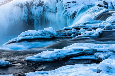 Icefall at the edge of the Godafoss waterfall at dawn, snow-covered landscape, Northern Iceland
