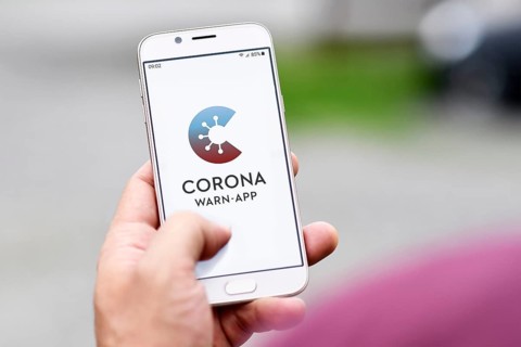 Germany, June 2020: Official German Corona Warning App on mobile phone held by hand on blurry