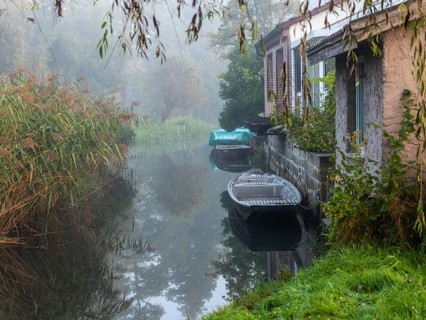 Autumn mist and lonely barges on the Spreewald river, between reeds and the edge of the village,