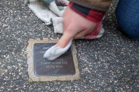 Polishing and cleaning a stumbling stone to commemorate the Night of Broken Glass on 9 November
