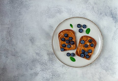 Rye bread with peanut paste and fresh blueberries, top view, no people
