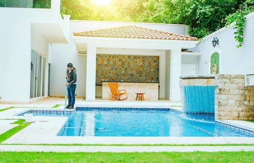 Man cleaning swimming pool with suction hose. Pool maintenance and cleaning with vacuum hose.