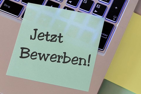 Notepad with the words APPLY NOW on a laptop