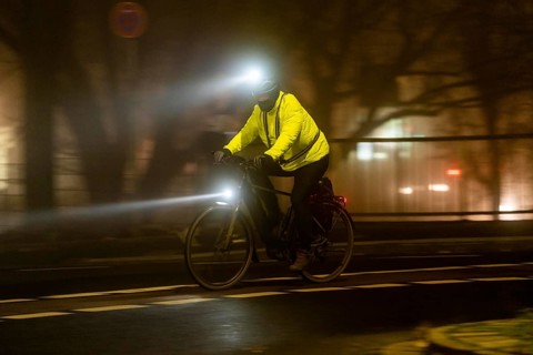 Cyclist with 2 lights and yellow cycling jacket, luminous, inner city traffic, fog, autumn, winter,