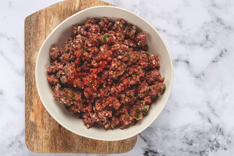 Raw minced meat, marinated with spices and herbs, in a bowl, minced meat with spices, top view,