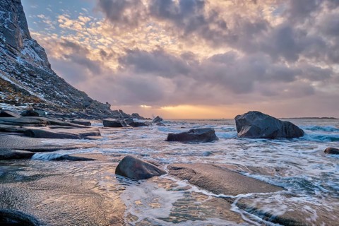 Rocks on beach of fjord of Norwegian sea in winteron sunset. Utakliev beach, Lofoten islands,