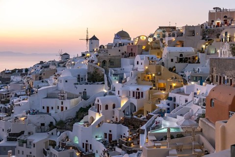 Cliff-side houses, villas and windmill in the village of Oia, Ia, at nightfall, Santorini, Greece,