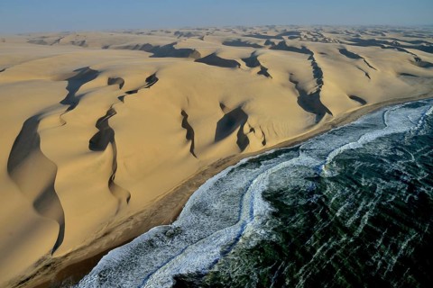 Aerial view, dunes in Namib desert, Atlantic Ocean, waves breaking on Namibian coast south of
