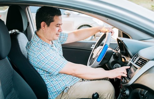 Driver man changing the radio station. Smiling driver tuning into the radio station. Distracted