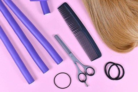 Hair styling concept with dark blond hair, elastic hair ties, comb, thinning shears, and papillote
