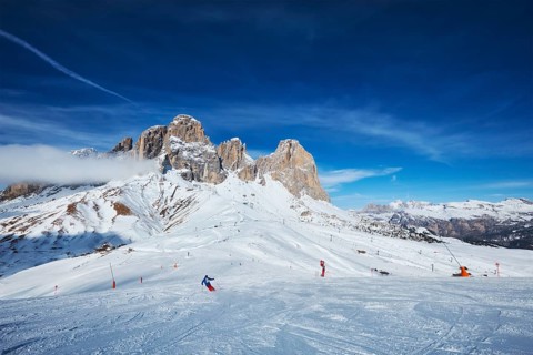 View of a ski resort piste with people skiing in Dolomites in Italy