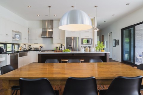 Open-concept dining and kitchen area with antique dining table with black leather and plastic