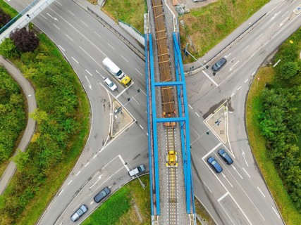 Railway bridge over road crossing with passing cars, track construction, rail delivery for Hermann