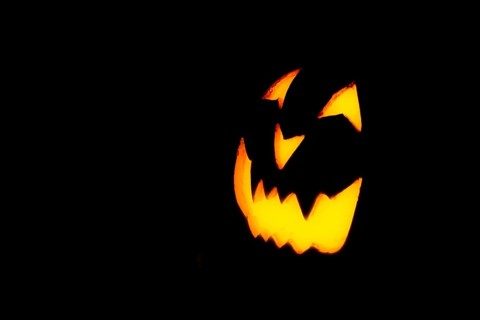 Glowing pumpkin face, Halloween, against a black background