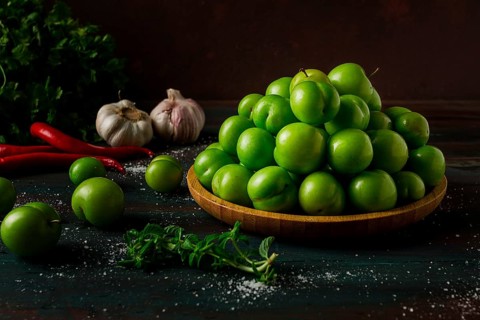 Tkemali, green cherry plum, with ingredients for sauce, cilantro, mint, hot pepper, garlic, on a