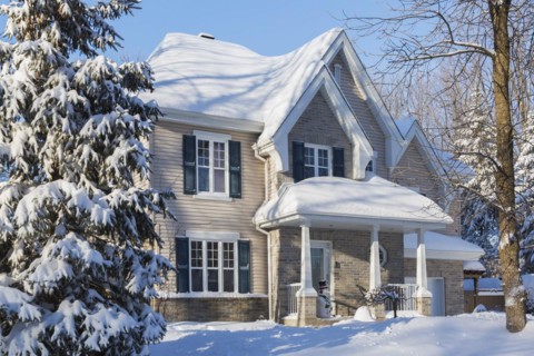 Country tan brick and vinyl cladded cottage style house facade with blue trim in winter, Quebec,