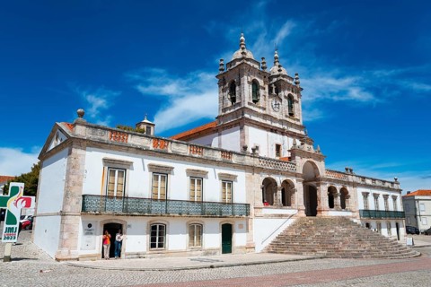 Baroque church building with striking towers, wide stone steps and bright facades under a blue sky,