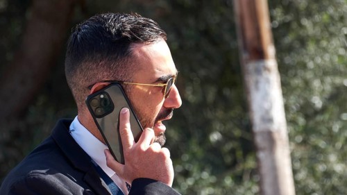 Man in a suit with sunglasses talking on a smartphone outdoors, visit of Federal President