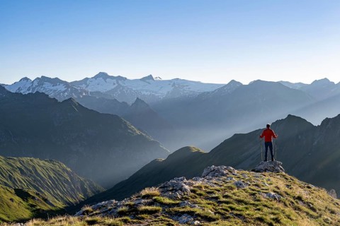 Mountaineer with poles on the summit of the Bachlenkenkopf at sunrise, atmospheric mountain