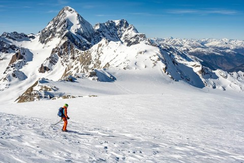 Mountaineer exploring a snow-covered landscape with impressive mountain peaks in the background,