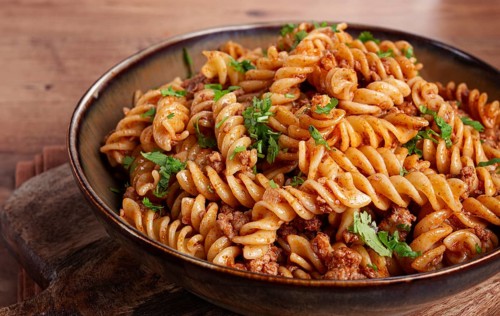 Pasta in the navy, pasta with minced meat, plate on a wooden table, homemade, fusilli pasta,