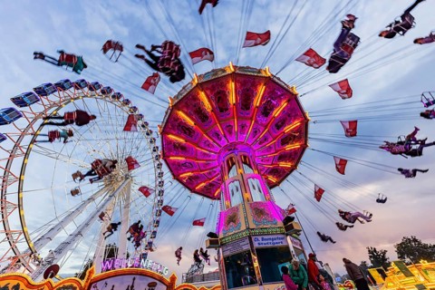 Chain carousel and Ferris wheel in the evening. 177th Cannstatter Volksfest at the Cannstatter