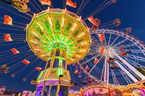 Illuminated carousel and Ferris wheel at night in a lively amusement park, funfair, wave flight,