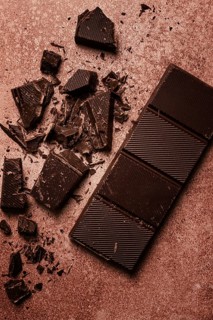 Chocolate bar, for the manufacture of confectionery, broken, crumbled, on a brown background, top