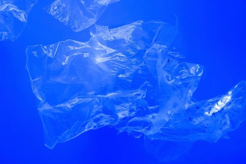 Transparent plastic bags floating underwater in blue ocean sea water, pollution by