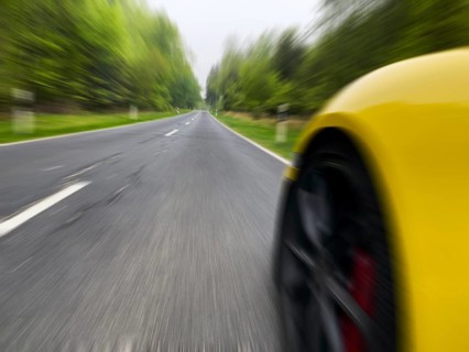 Photo with low camera perspective of car speeding at high speed without speed limit on country road