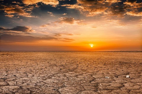 Global worming concept, cracked scorched earth soil drought desert landscape dramatic sunset