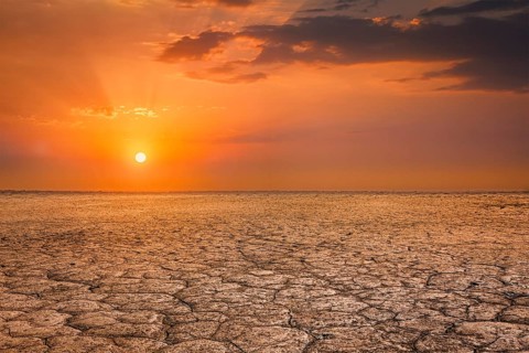 Global worming concept, cracked scorched earth soil drought desert landscape dramatic sunset