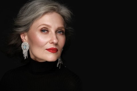 Portrait of a beautiful elderly woman in a white shirt with classic makeup and gray hair